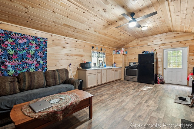 kitchen featuring vaulted ceiling, freestanding refrigerator, light wood-style floors, wood walls, and gas stove
