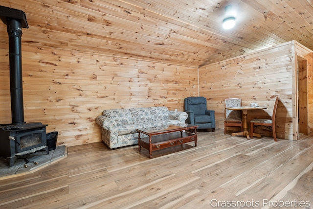 sitting room featuring wooden walls, hardwood / wood-style floors, a wood stove, and wooden ceiling