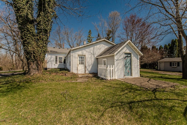 rear view of property with a lawn and an outdoor structure