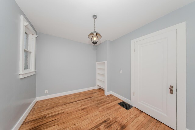 spare room with baseboards, light wood-style flooring, and visible vents