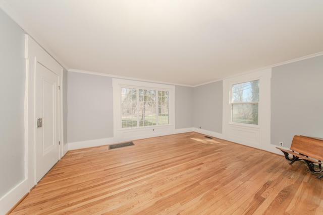 spare room with plenty of natural light, visible vents, light wood-style floors, and crown molding