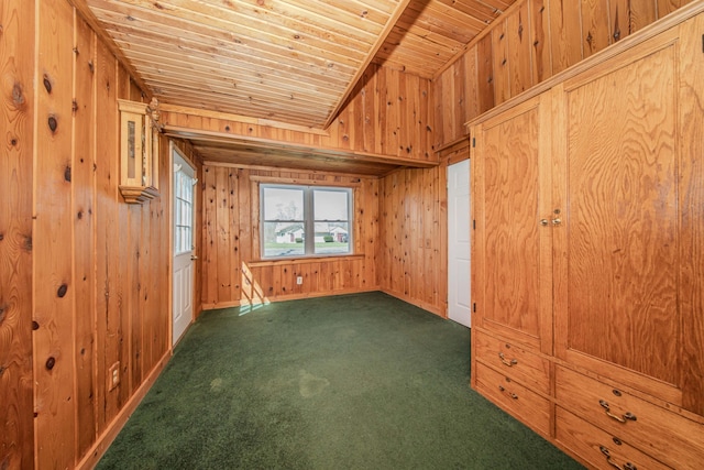 interior space with wooden walls, dark colored carpet, vaulted ceiling, baseboards, and wood ceiling