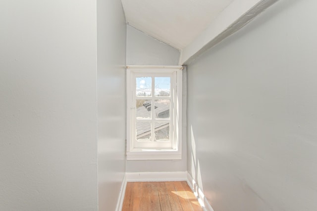 interior space with baseboards, vaulted ceiling, and light wood-style flooring