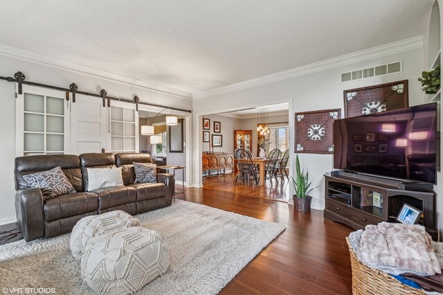 1888 Boardwalk, Saint Joseph, MI 49085 - living room featuring a barn door, wood finished floors, visible vents, crown molding, and a notable chandelier
