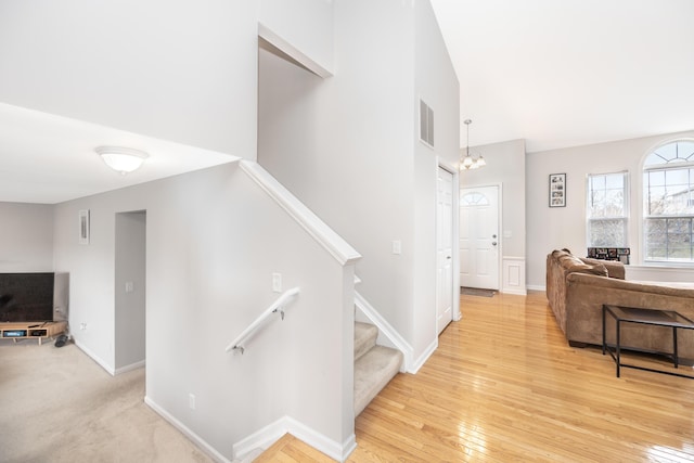 interior space with hardwood / wood-style flooring, visible vents, baseboards, and a notable chandelier