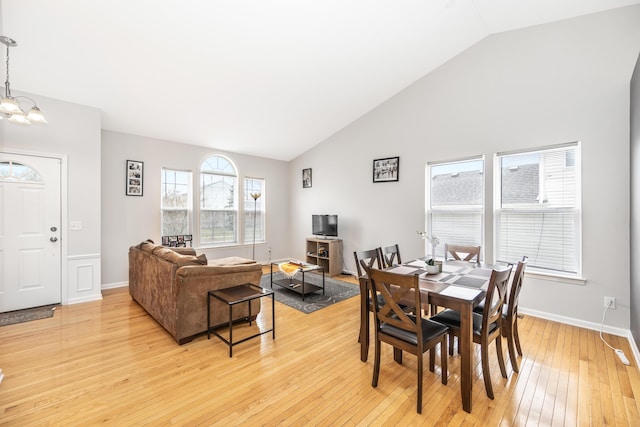 dining space with high vaulted ceiling, baseboards, an inviting chandelier, and light wood-type flooring