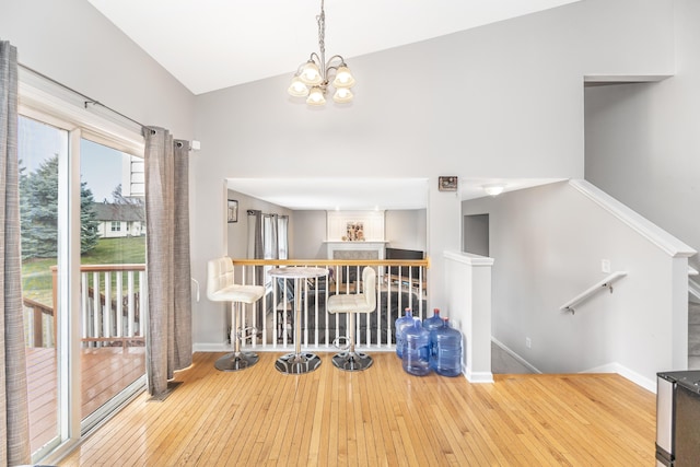 dining space featuring baseboards, hardwood / wood-style flooring, and high vaulted ceiling