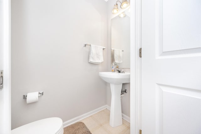 bathroom featuring toilet, a sink, and baseboards