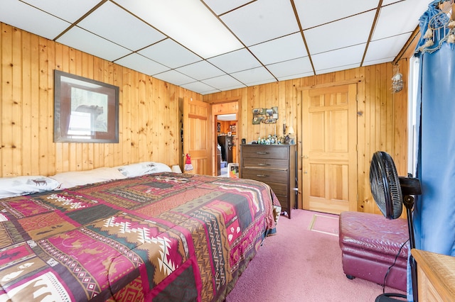 carpeted bedroom featuring wooden walls and a drop ceiling