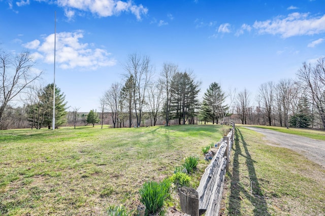 view of yard featuring fence, a rural view, and dirt driveway