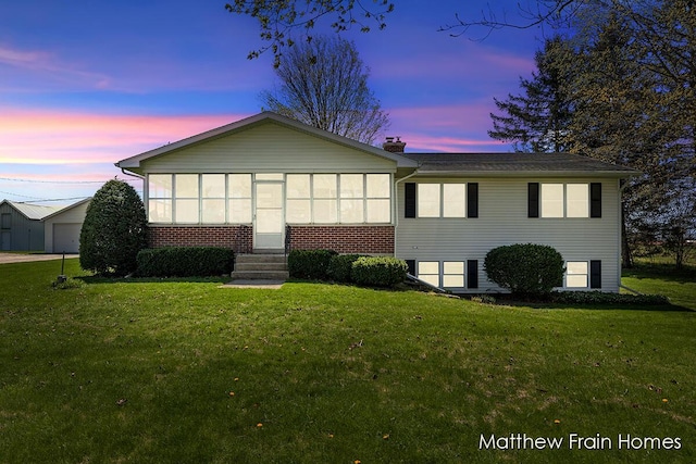 view of front facade featuring entry steps, a yard, and brick siding