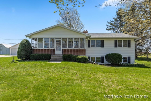 view of front of property featuring brick siding, a sunroom, a chimney, and a front yard
