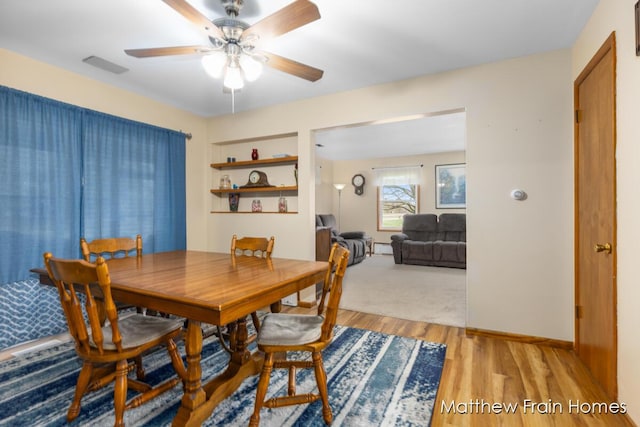 dining room featuring light wood-style flooring, visible vents, baseboards, and ceiling fan