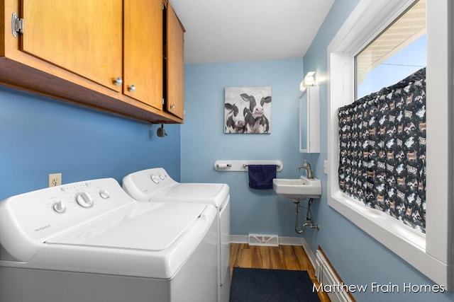 laundry area featuring wood finished floors, a sink, separate washer and dryer, cabinet space, and baseboards