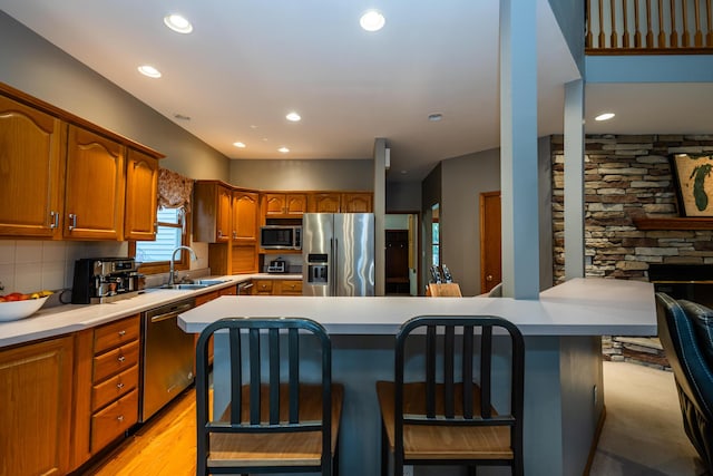 4569 Terra Ln, Saint Joseph, MI 49085 - kitchen featuring appliances with stainless steel finishes, brown cabinetry, a sink, a kitchen breakfast bar, and light countertops