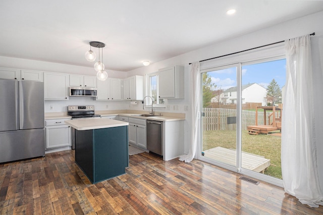kitchen with a sink, light countertops, appliances with stainless steel finishes, visible vents, and a kitchen island