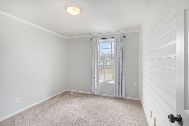 carpeted empty room featuring baseboards and crown molding