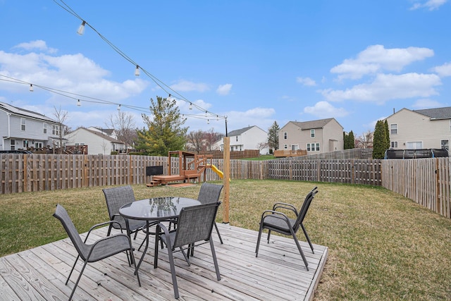wooden terrace featuring a fenced backyard, outdoor dining area, a yard, and a residential view