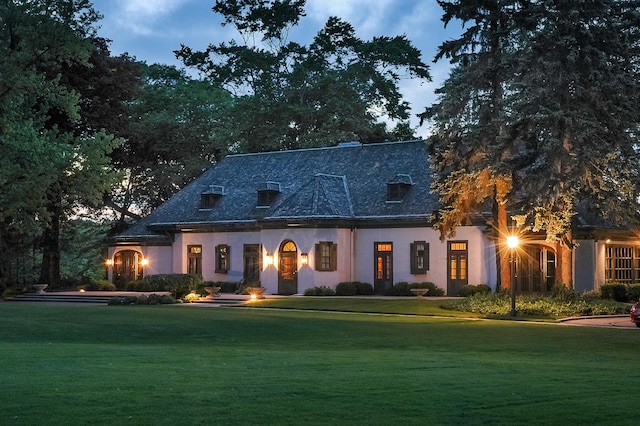 view of front of house with a high end roof, a front yard, and stucco siding