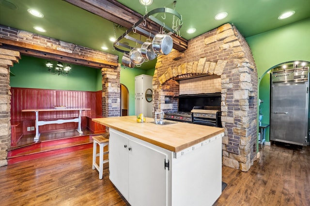 kitchen with white cabinets, dark wood-style floors, an inviting chandelier, decorative columns, and wood counters