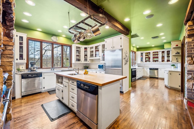 kitchen featuring wood counters, light wood-type flooring, white cabinetry, backsplash, and appliances with stainless steel finishes