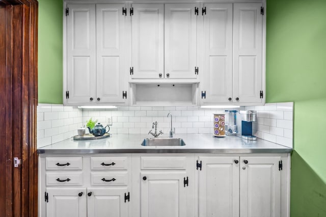 kitchen with decorative backsplash, white cabinetry, a sink, and light countertops