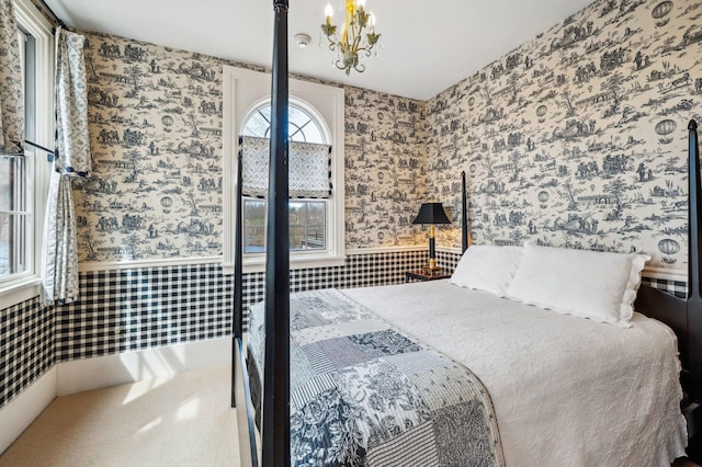 bedroom with wallpapered walls, wainscoting, and an inviting chandelier