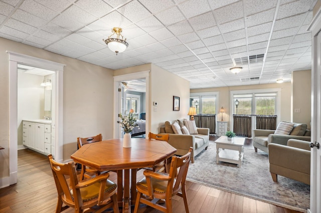 dining area with wood-type flooring, a ceiling fan, and a paneled ceiling