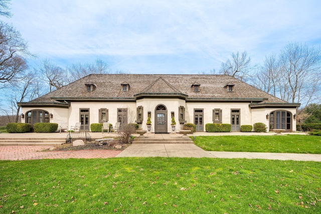 french country home featuring stucco siding, a front lawn, and french doors