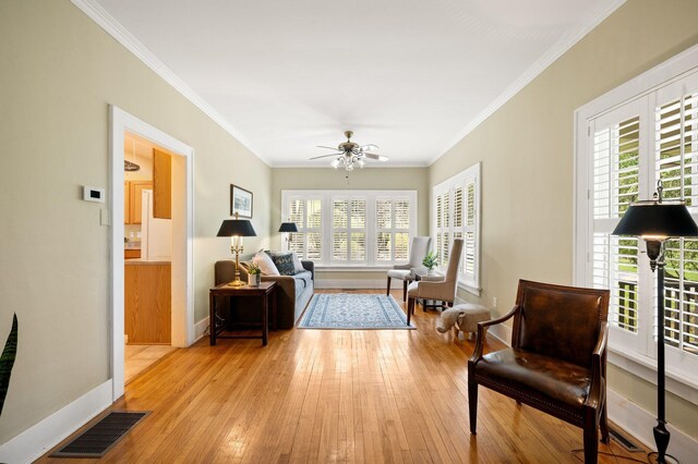 living area with visible vents, ornamental molding, baseboards, and ceiling fan