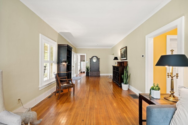 living room with visible vents, light wood finished floors, baseboards, and ornamental molding