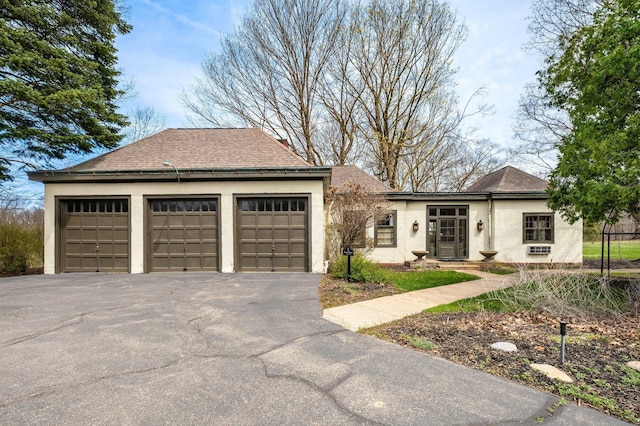 ranch-style house with a garage, roof with shingles, and stucco siding