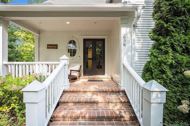view of exterior entry with covered porch and french doors