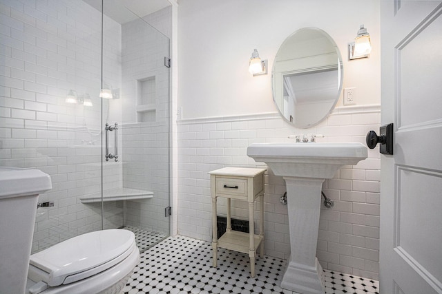 bathroom with a stall shower, tile walls, a wainscoted wall, toilet, and tile patterned flooring