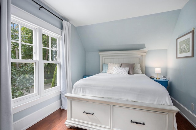 bedroom with lofted ceiling, dark wood-type flooring, and baseboards