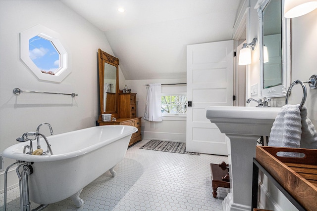 full bath featuring lofted ceiling, a soaking tub, and baseboards