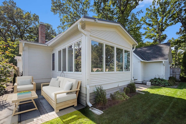 view of side of property with a chimney, an outdoor hangout area, a yard, a sunroom, and a patio