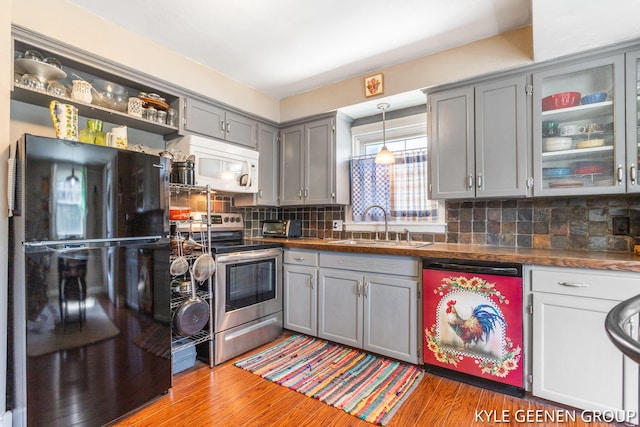 kitchen featuring freestanding refrigerator, white microwave, dishwasher, electric stove, and gray cabinetry