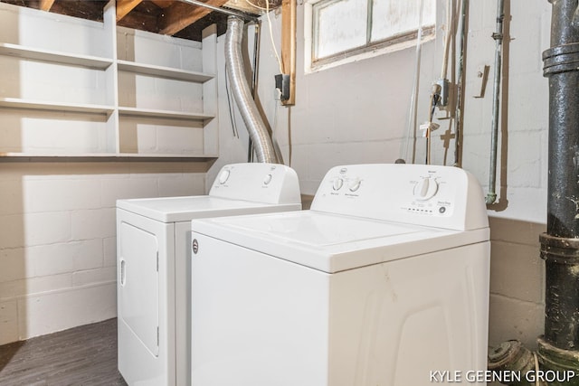 washroom featuring washing machine and dryer, concrete block wall, and dark wood-style flooring