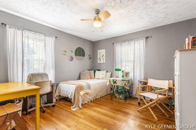 bedroom featuring light wood-style floors, a textured ceiling, and a ceiling fan