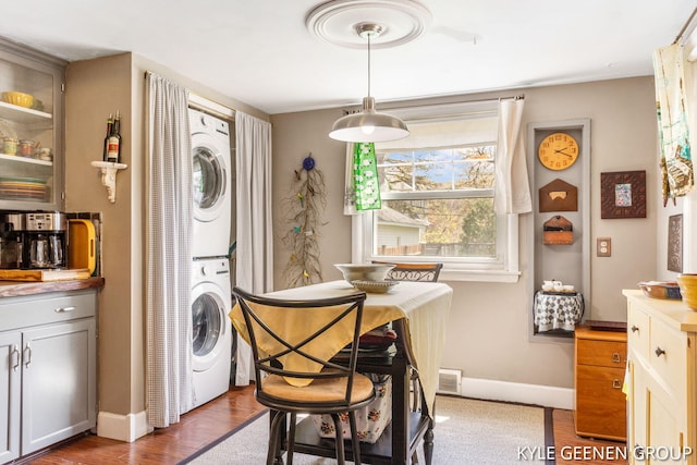 dining space with stacked washer / dryer, baseboards, and dark wood-style floors