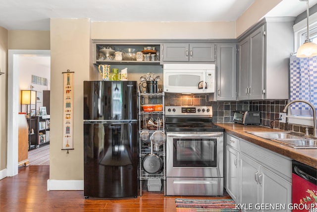 kitchen featuring stainless steel electric stove, freestanding refrigerator, white microwave, dishwasher, and a sink