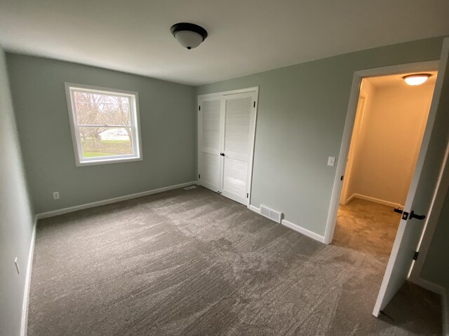 10 Meadow Hills Ln, Fremont, MI 49412 - unfurnished bedroom with baseboards, carpet floors, visible vents, and a closet