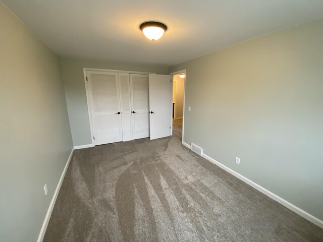 10 Meadow Hills Ln, Fremont, MI 49412 - unfurnished bedroom featuring baseboards, visible vents, dark carpet, and a closet