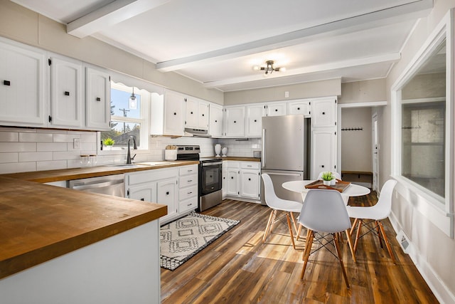 kitchen with a sink, wooden counters, beamed ceiling, dark wood finished floors, and appliances with stainless steel finishes
