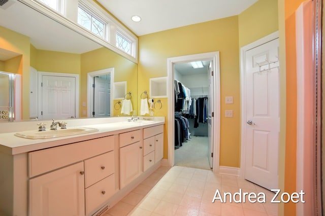 bathroom with double vanity, a spacious closet, tile patterned flooring, and a sink