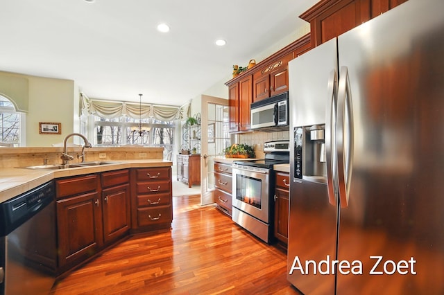kitchen with a sink, stainless steel appliances, light countertops, dark wood finished floors, and backsplash