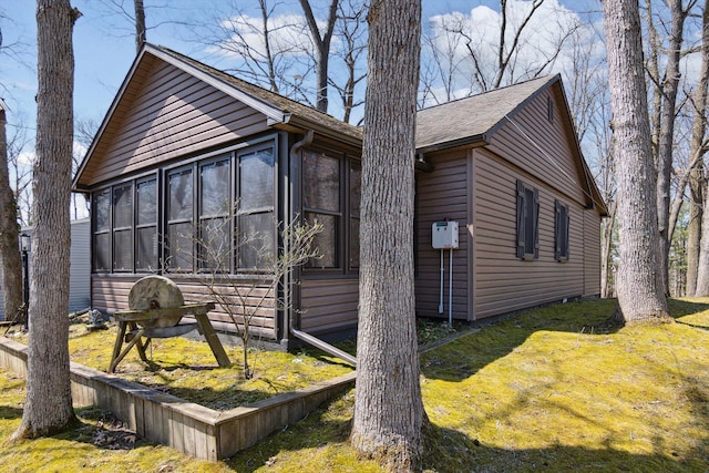 view of side of home featuring a sunroom and a yard