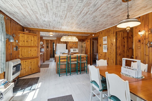 dining area featuring wood ceiling, heating unit, and wooden walls