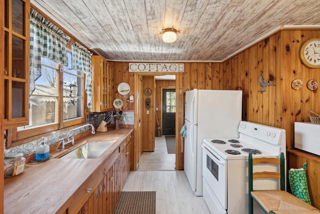 kitchen featuring wood walls, wooden ceiling, white appliances, and a sink